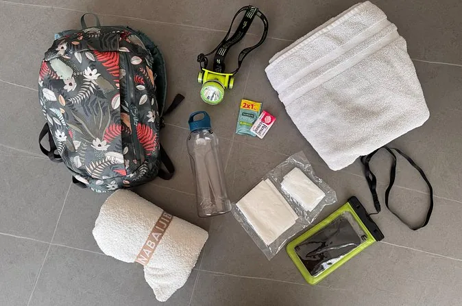 Ein Rucksackset mit Handtuch, Stirnlampe, Trinkflasche und wasserdichter Handyhülle